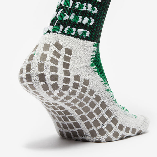 Close-up of a green and gray sock with textured sole on a white background