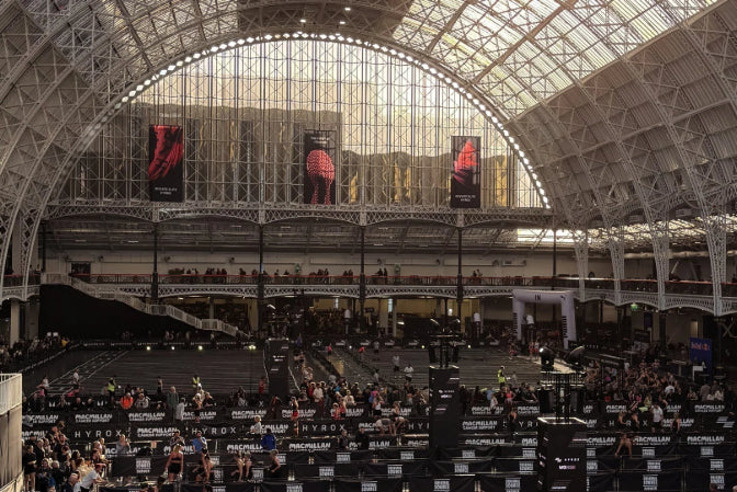 Large indoor arena with a high ceiling and large windows, filled with people.