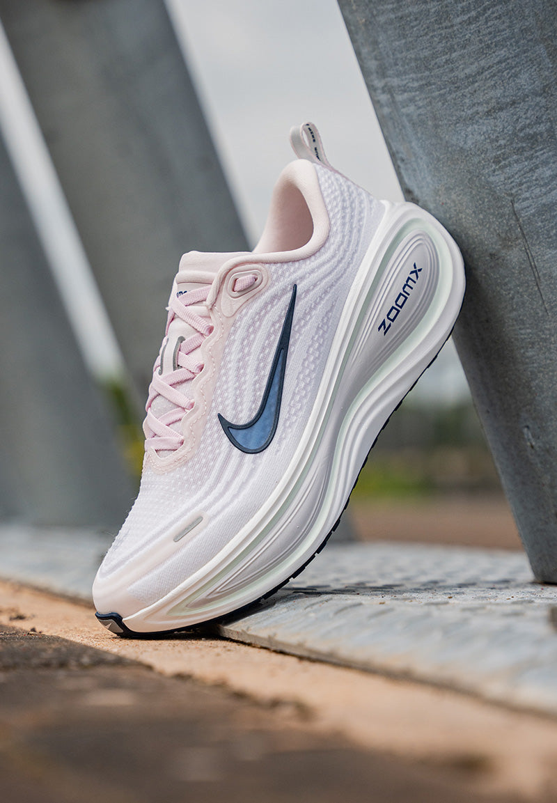 Pink and white running shoe with Nike logo on a blurred background
