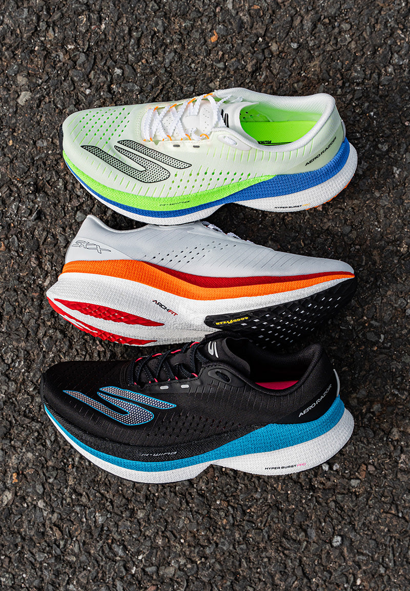 Three running shoes stacked on a textured surface