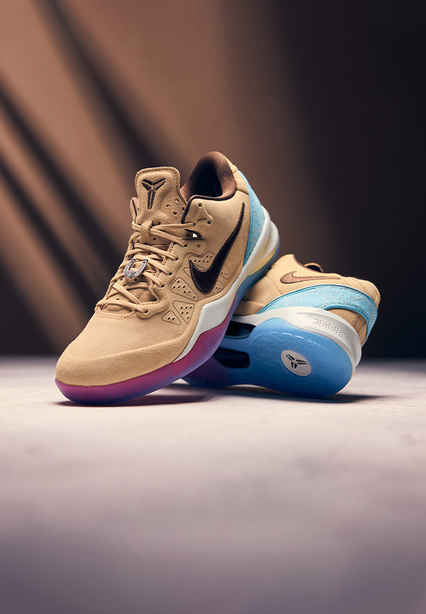 Pair of tan and blue sneakers on a gradient background