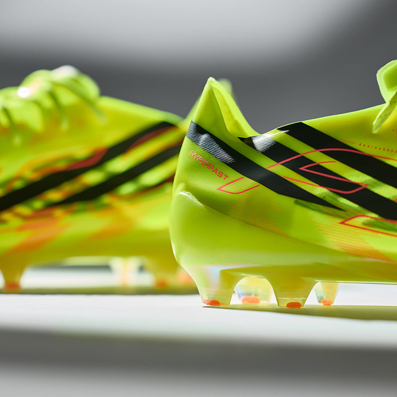 Neon green football boots with black accents on a grey background