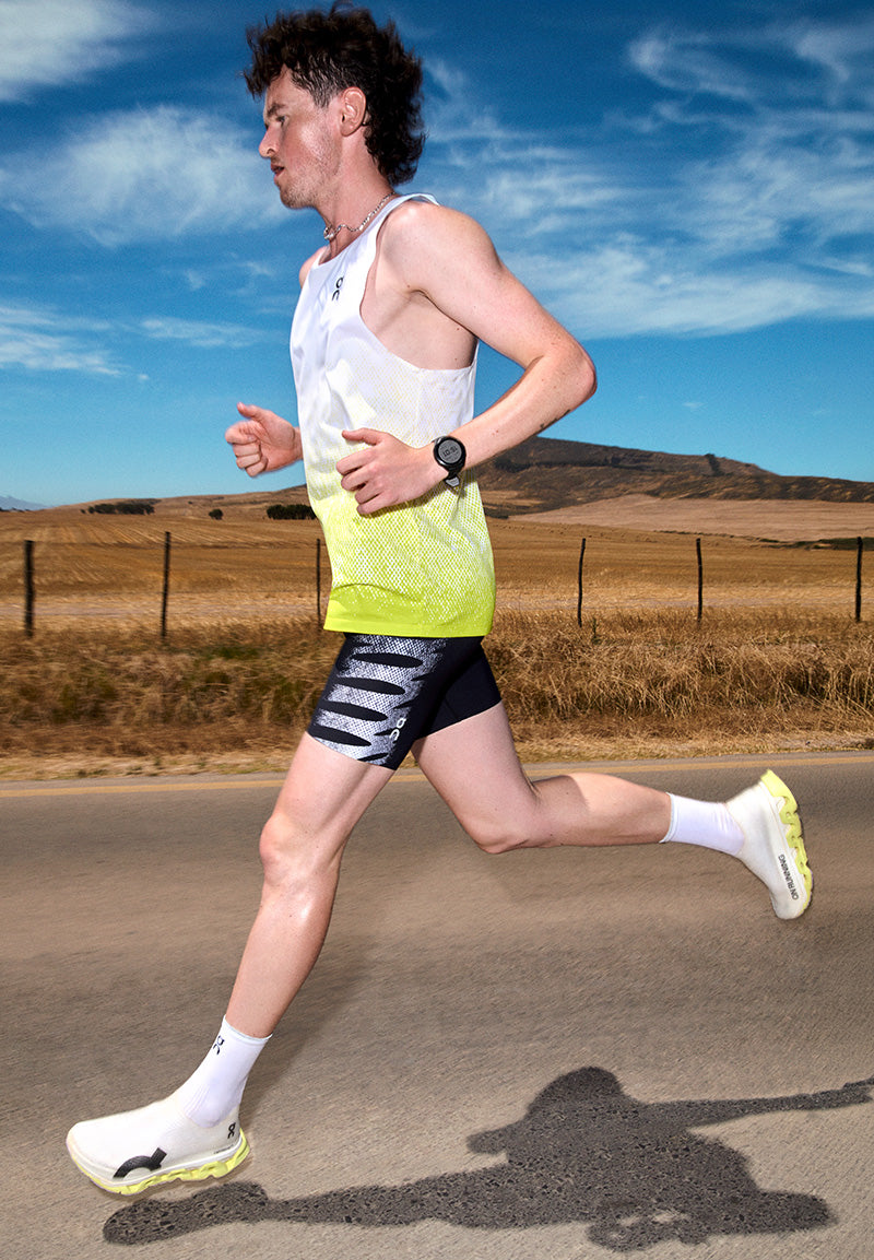Person running on a road with a clear sky and mountains in the background